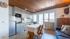 A compact kitchen with modern appliances, a dining area with a table and chairs, and a cozy living space with a sofa and a window. - One bedroom Apartment in Canazei (Campitello di Fassa)