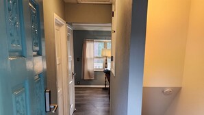 Ein Flur mit einer blauen Tür, einem Teppich und einer Treppe.