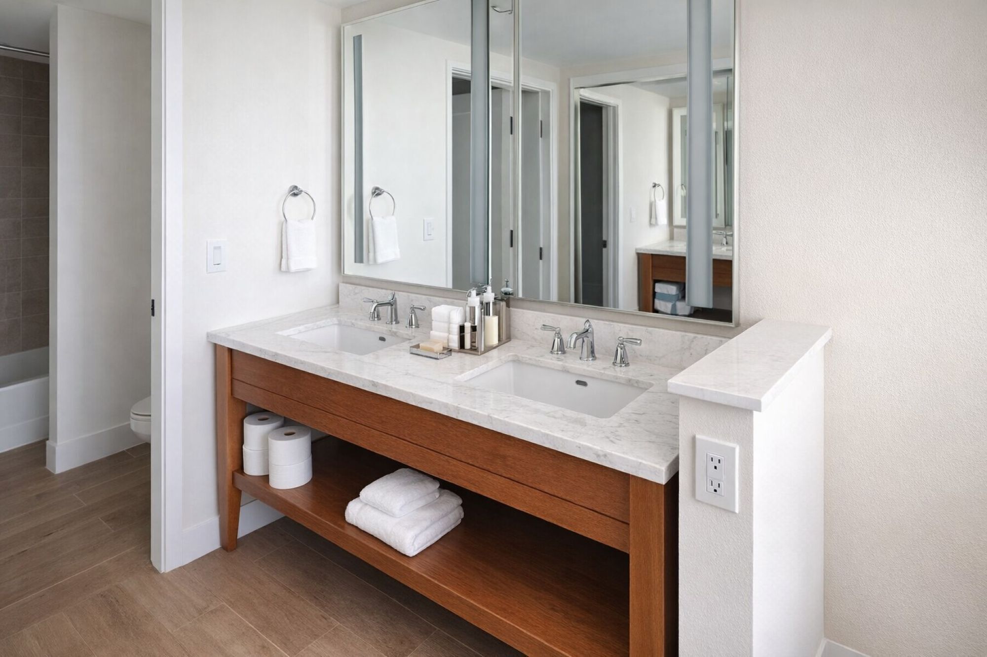 A modern bathroom with two sinks, a large mirror, wooden vanity, and a shower area.