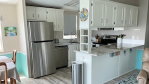 A modern kitchen with white cabinets, stainless steel appliances, and a marble countertop.