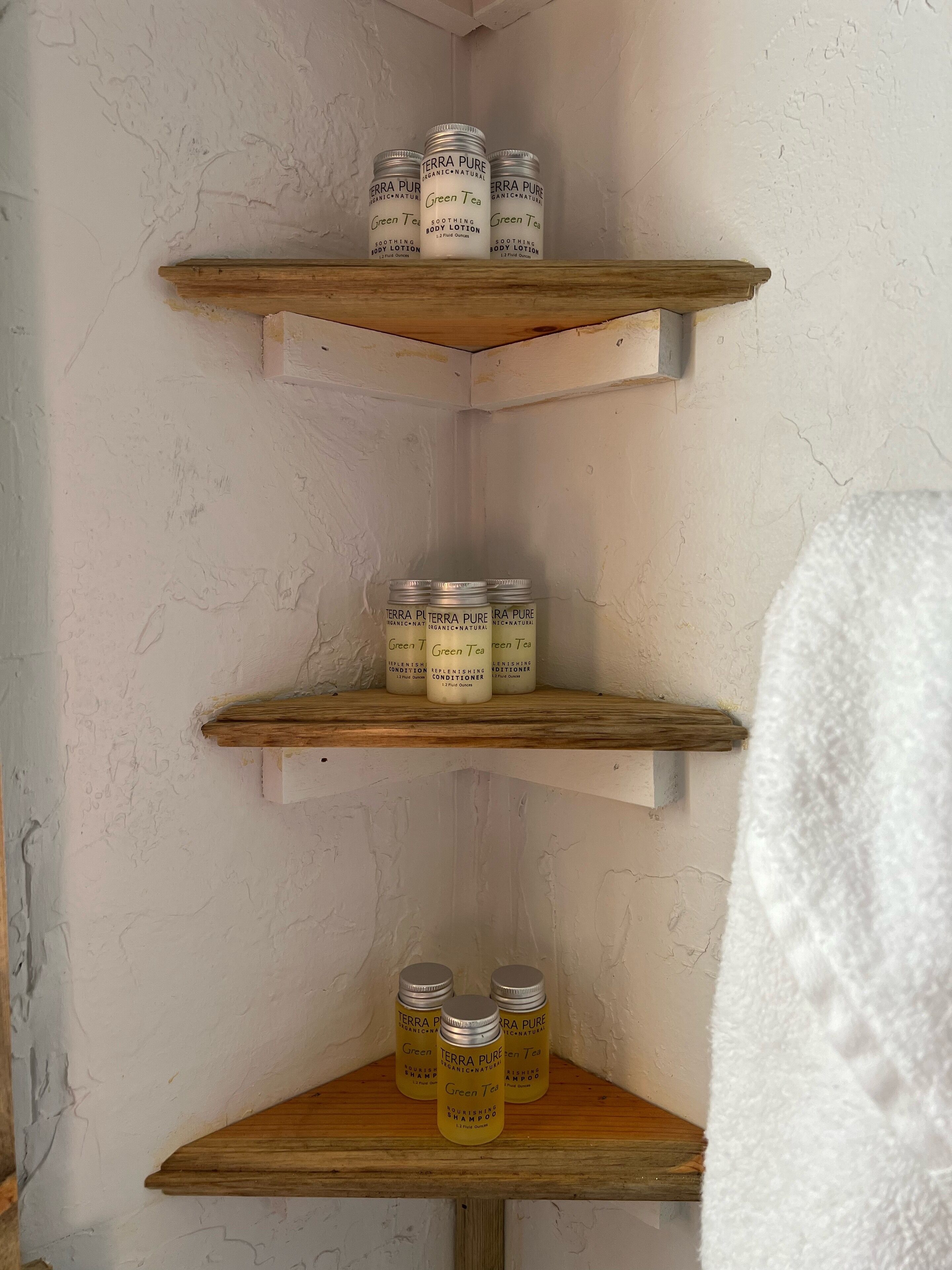A bathroom shelf with three shelves holding various Terra Pure products.