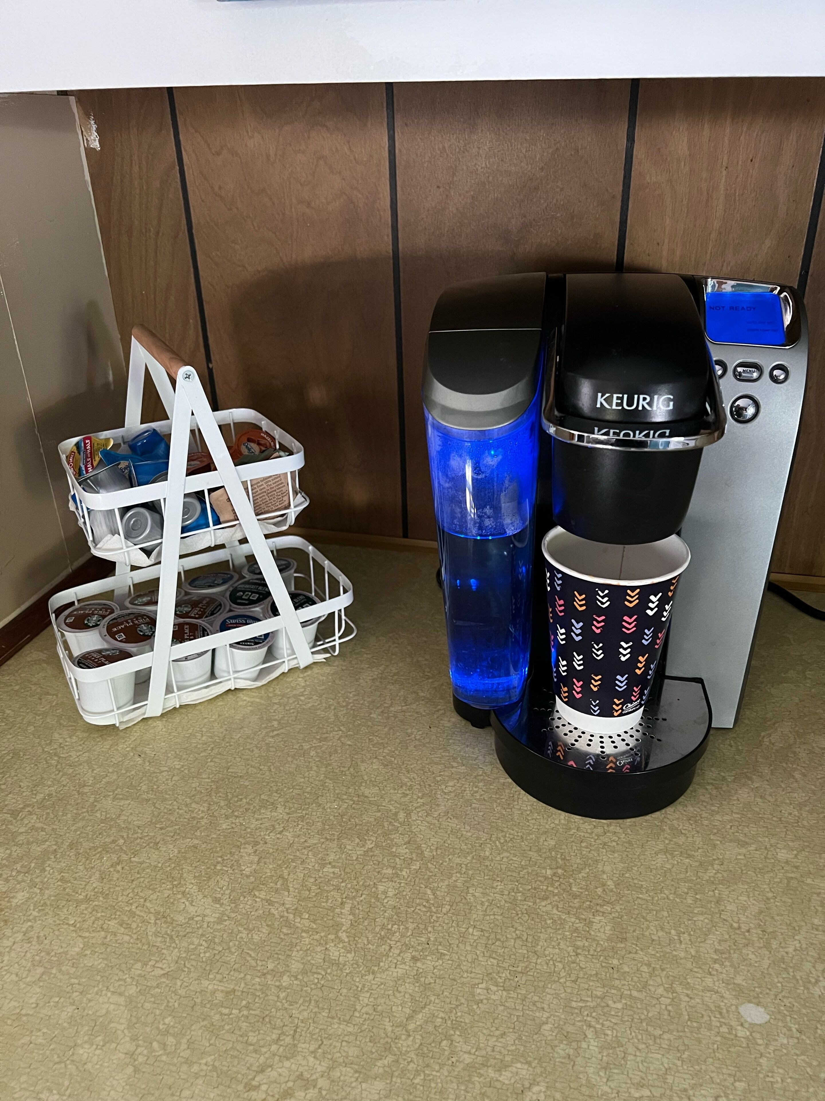 A coffee maker with a water reservoir and a coffee cup holder.