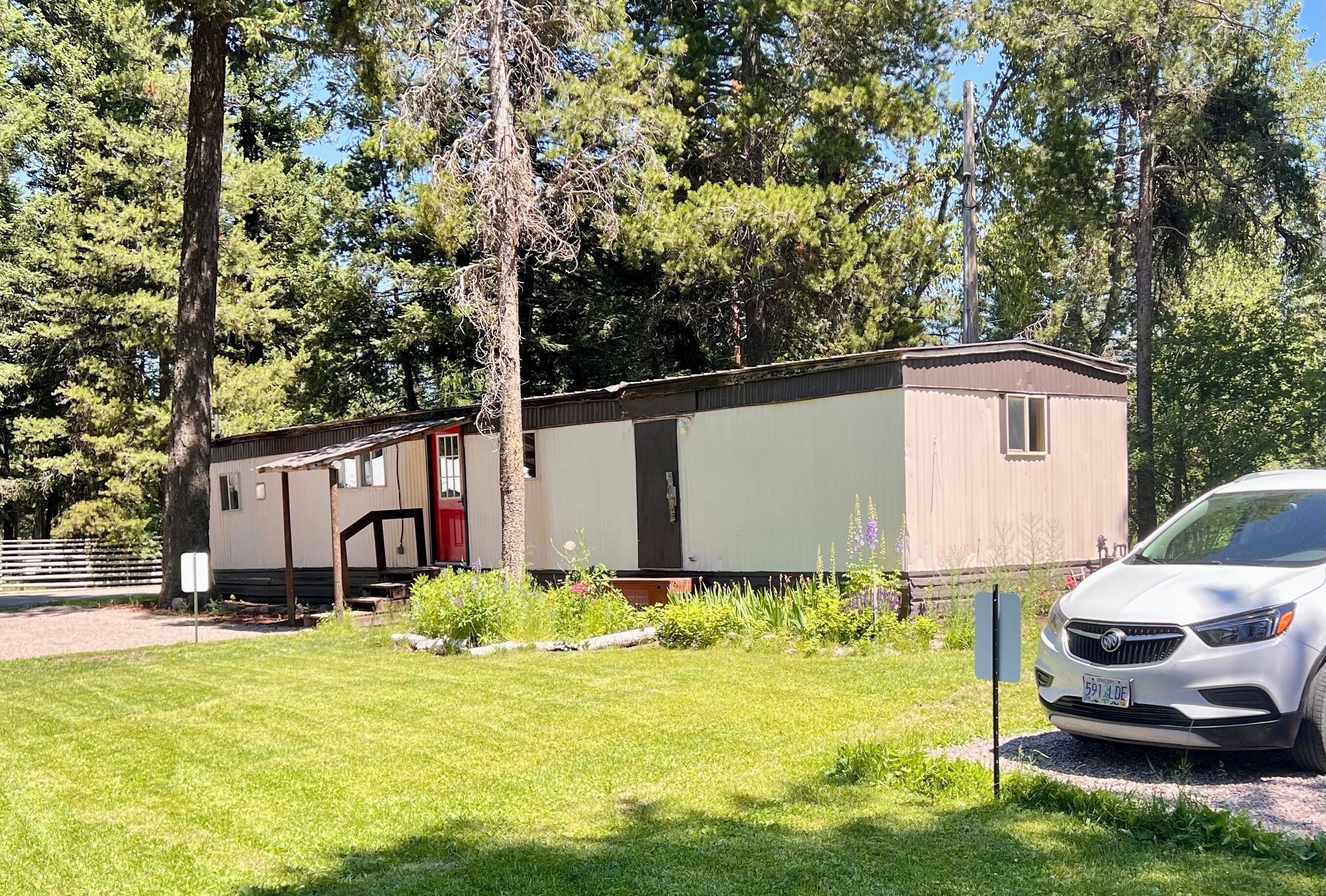 A mobile home with a red door, a covered porch, and a small window.