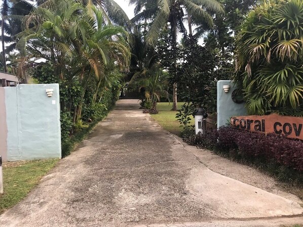 A pathway leading to a building with a sign reading "coral cov" surrounded by lush tropical vegetation.