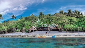 A beach resort with a wooden structure, palm trees, and a clear blue sky.