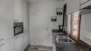 Una cocina moderna con horno integrado, cafetera y lavamanos.