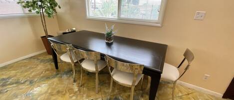 A dining area with a marble floor, a dark wooden table, and four chairs.