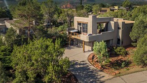 Una casa moderna con patio, rodeada de árboles y montañas.