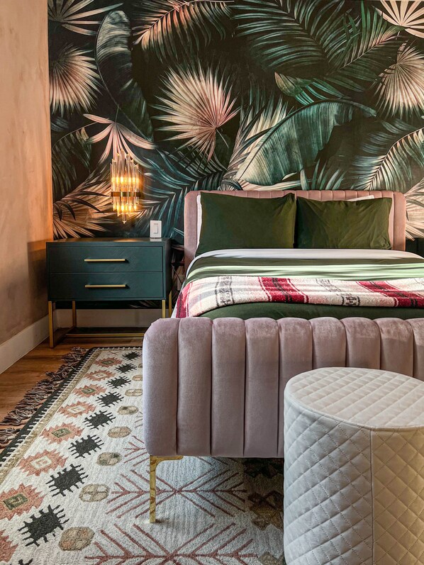 A bedroom with a bed, a nightstand, a lamp, and a patterned rug.
