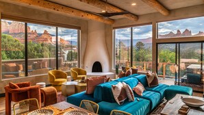 Amplia sala de estar con un sofá grande, sillones y chimenea, con vistas a un paisaje pintoresco.