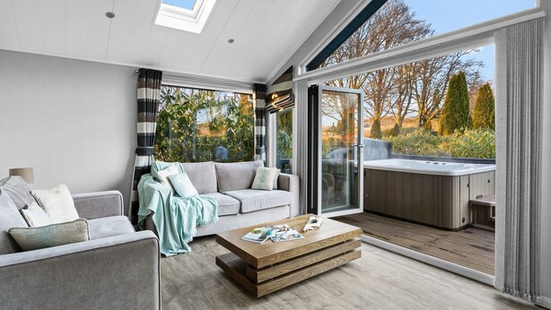 A modern living room with a sofa, a coffee table, and a hot tub area. - Killington Lodge, Kentisbury Grange (Barnstaple)