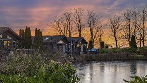 A lakeside property with modern cabins, a clear view of the water, and a sunset sky. - Killington Lodge, Kentisbury Grange (Barnstaple)