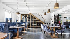 A restaurant with blue upholstered booths, round tables, and hanging pendant lights. - Killington Lodge, Kentisbury Grange (Barnstaple)
