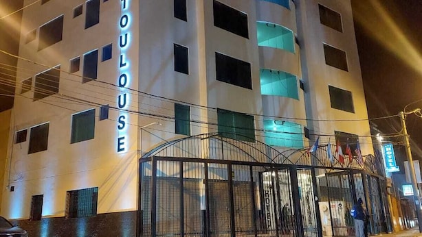 A multi-story hotel with a prominent entrance gate and illuminated signage. - Hotel Toulouse Arequipa (Arequipa)