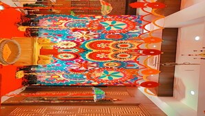 Una habitación con una alfombra grande y colorida de diseño geométrico, suelo de madera y un diseño moderno en el techo.