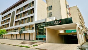 Un hotel de varios pisos con fachada moderna, un acceso cubierto y un letrero visible para servicio de recogidas.