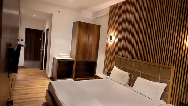 Una habitación de hotel moderna con una cama grande, un armario de madera y un escritorio con una silla.