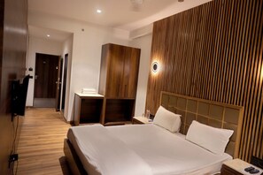 A modern hotel room with a large bed, wooden wardrobe, and a desk with a chair. - The Park Celebration (Surat)