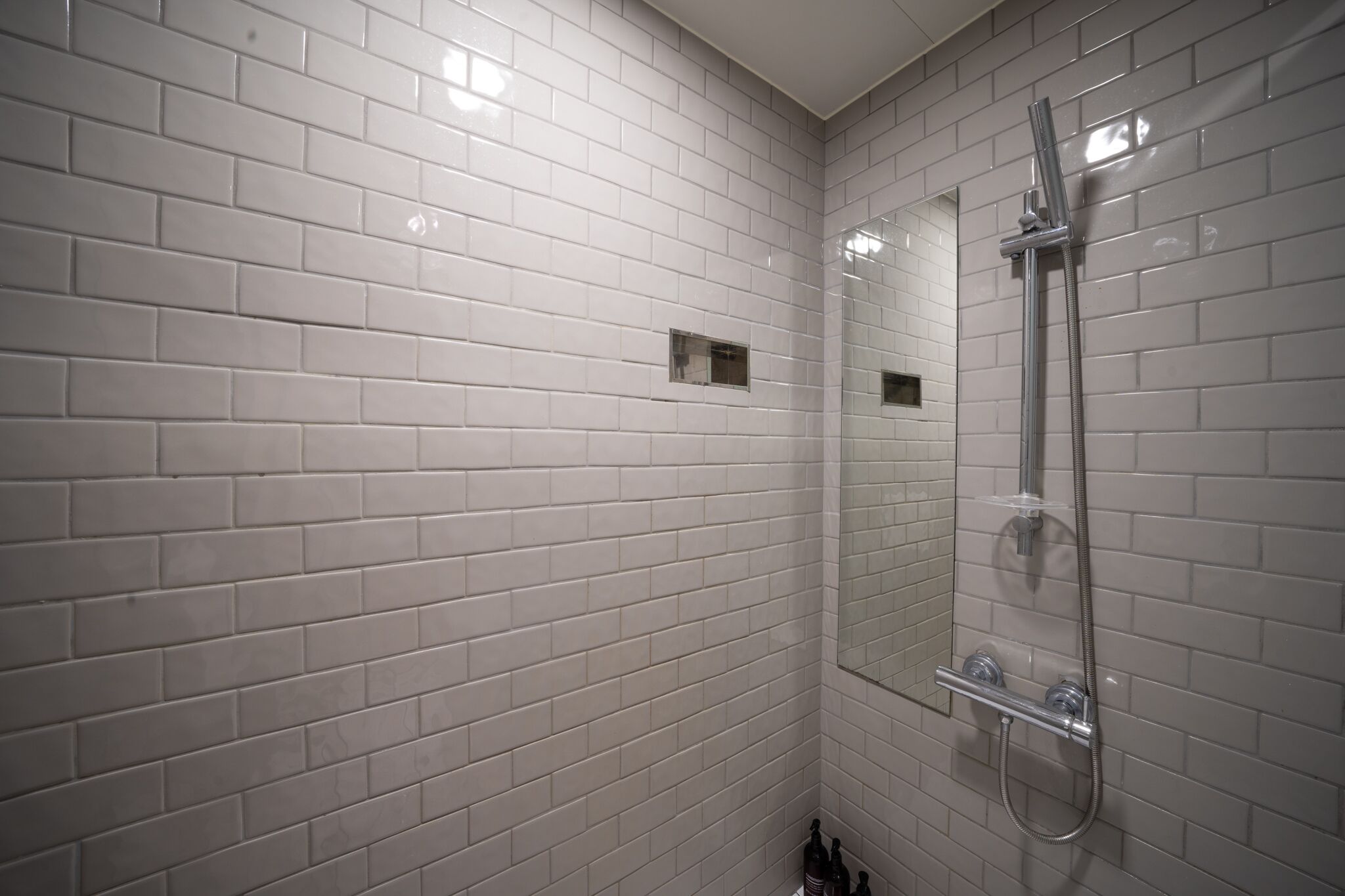 A bathroom with white tiled walls and a glass-enclosed shower area.
