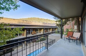 Un balcon avec vue sur un immeuble et une piscine.