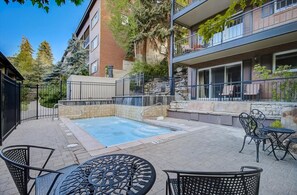 Une piscine sur le toit, dotée d’un jacuzzi, entourée d’un espace de détente extérieur et d’un mur en pierre.