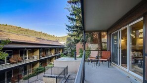 Un balcón de hotel con piscina, mobiliario exterior y vistas a un paisaje montañoso.