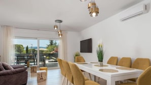 A modern living room with a sofa, a dining table with chairs, and a view of a pool and outdoor area. - Villa Palma by Interhome (Krk/Pinezići)