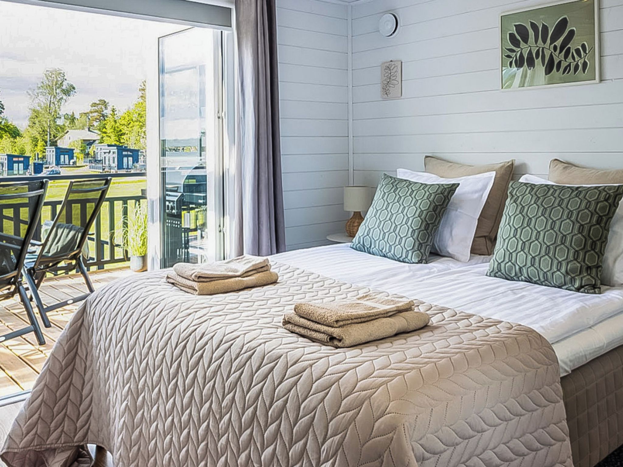 Ein Hotelzimmer mit Bett, Stuhl, Tisch und Blick ins Freie.
