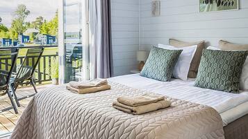 Ein Hotelzimmer mit Bett, Stuhl, Tisch und Blick ins Freie.