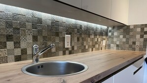 A modern kitchen with a wooden countertop, stainless steel sink, and patterned backsplash. - Ilse EG Süd-West by Interhome (Fiesch)