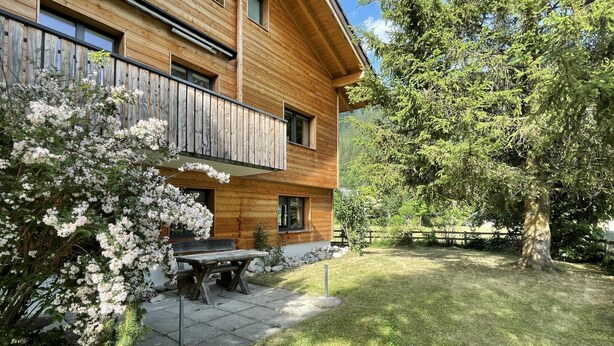 A wooden house with a balcony, a stone bench, and a grassy yard. - Ilse EG Süd-West by Interhome (Fiesch)