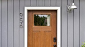 A wooden front door with a small window, a mailbox, and a wall-mounted light fixture. - H Studio Close to Downtown Beaches Wineries (Traverse City)