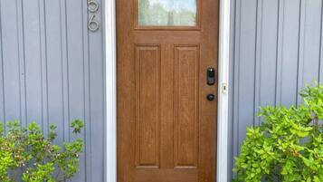 Puerta de madera con un panel de vidrio, buzón y felpudo.