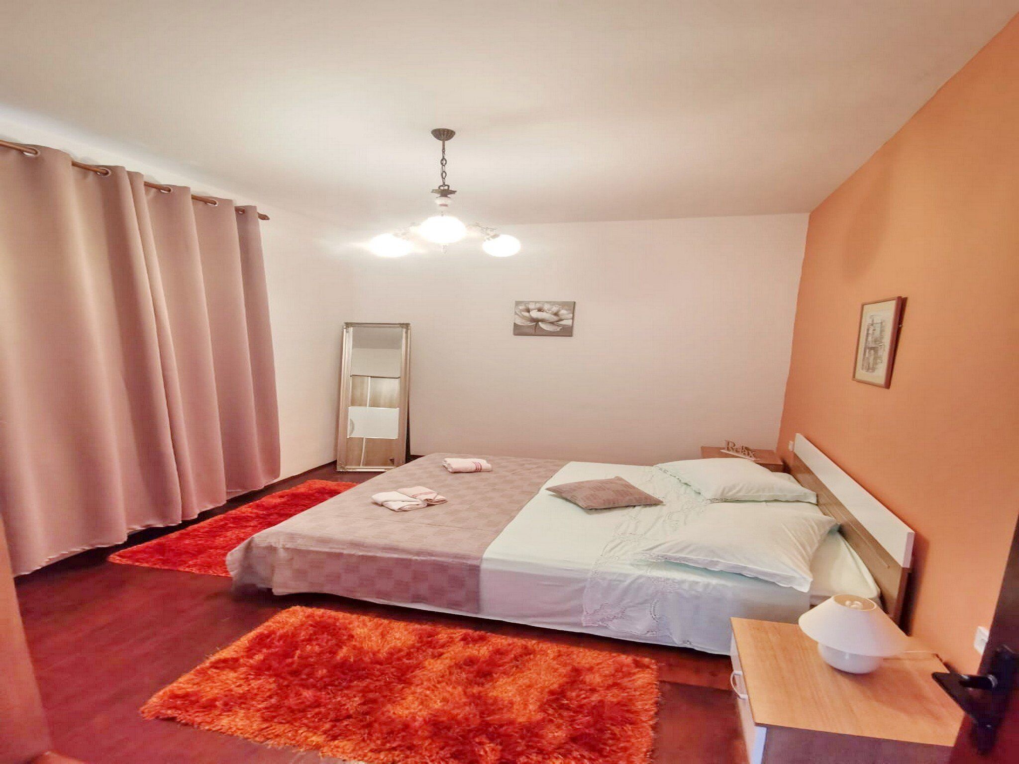 Un dormitorio con cama, mesita de noche, espejo y luz en el techo.