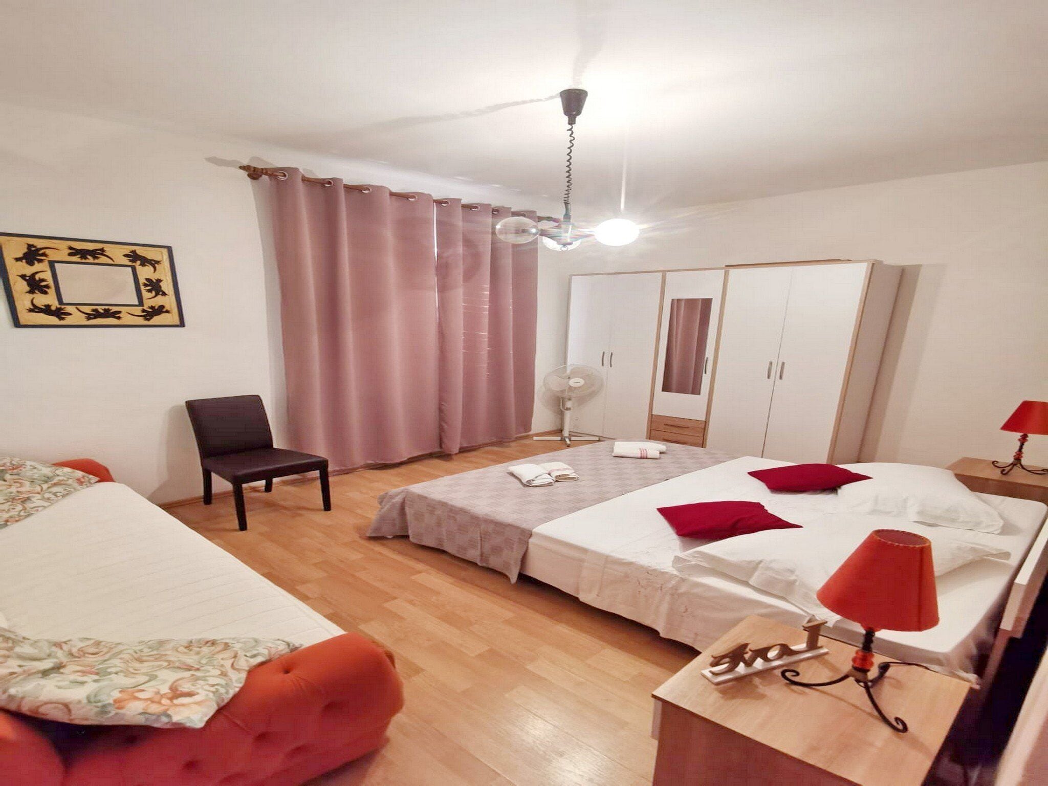 Une chambre d’hôtel avec deux lits, une armoire, une chaise, un bureau et un ventilateur de plafond.