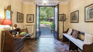 A room with a wooden desk, a bench, a chandelier, and framed artwork on the walls. - Villa Rinaldi 6 in Carpineta (Monteriggioni)