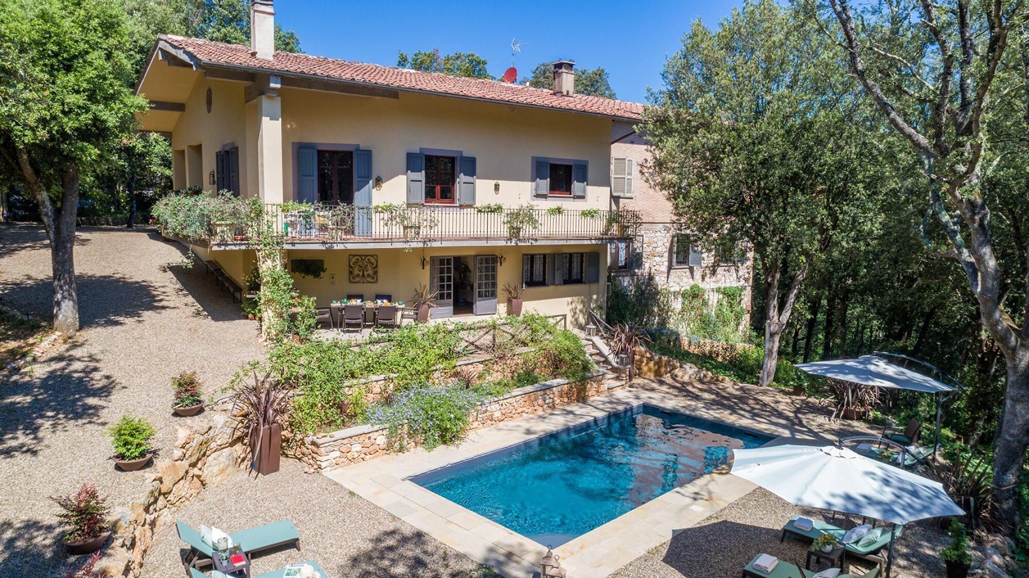 A two-story house with a swimming pool, outdoor seating, and a garden.