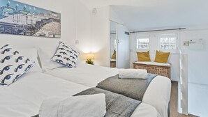 A hotel room with two beds, a large window, and a painting of a cityscape. - On the Water 4 By My Getaways (Brighton)