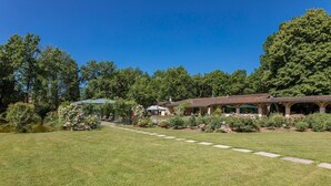 A house with a covered patio, surrounded by a well-maintained lawn and trees. - Villa Mimmina 8 in Civitella in Val di Chiana (Civitella in Val di Chiana)