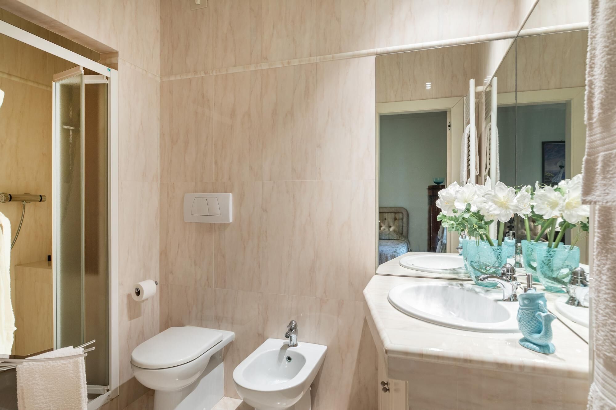 A bathroom with a toilet, bidet, sink, and mirror.