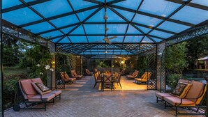 An outdoor covered patio with a table and chairs, surrounded by a metal fence and plants. - Villa Mimmina 8 in Civitella in Val di Chiana (Civitella in Val di Chiana)