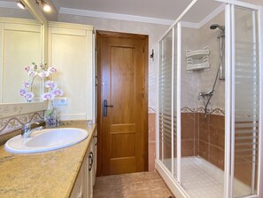 Een badkamer met een houten deur, een wastafel en een douchecabine.