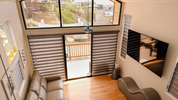 Ein modernes Wohnzimmer mit einer Couch, einer gepolsterten Bank und einem großen Fenster mit Blick ins Freie.