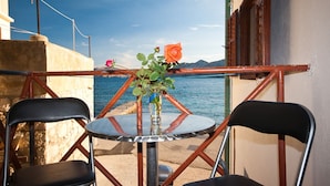 A table with chairs and a vase of flowers on a balcony overlooking a body of water. - First row to the sea (Baska)