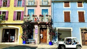 Una hilera de edificios coloridos con balcones, un coche aparcado y un banco al frente.