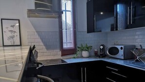 Una cocina moderna con gabinetes negros, encimera de acero inoxidable, microondas y cafetera.