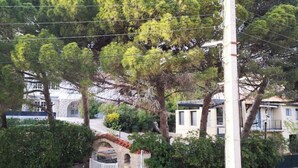 Zona residencial con un muro de piedra, una reja blanca y un coche estacionado.