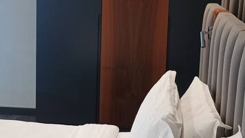 A modern hotel room with a bed, a wooden accent wall, and a grey headboard.