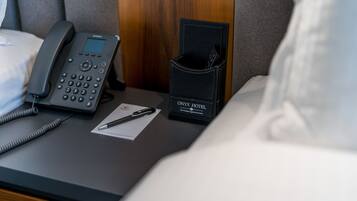 A hotel room with a bedside phone, a pen, and a black wallet with the hotel name on it.