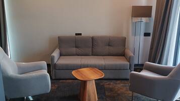 A modern living room with a grey sofa, two grey armchairs, and a wooden coffee table.